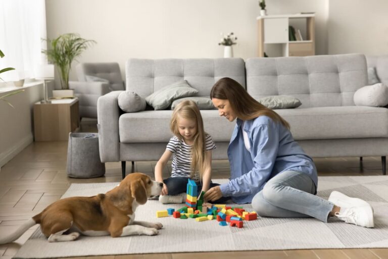 Woman and girl playing in living room on carpet with dog